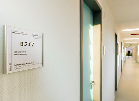 Das Bild zeigt einen Schulflur der Dothanschule mit dem Trschild der Schulleitung B.2.07