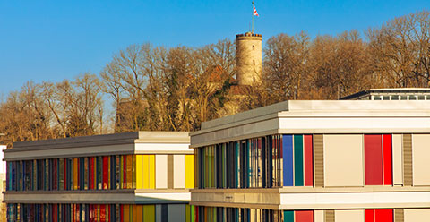 Sicht auf das Kinderzentrum mit farbigen Fenstern und dahinter ist die Sparrenburg zu sehen